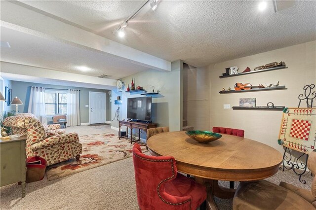 carpeted dining area with track lighting, a textured ceiling, and visible vents