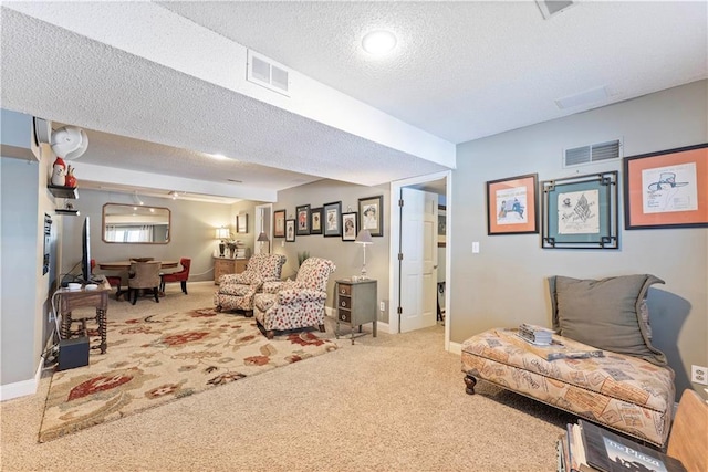 carpeted living area featuring baseboards, a textured ceiling, and visible vents