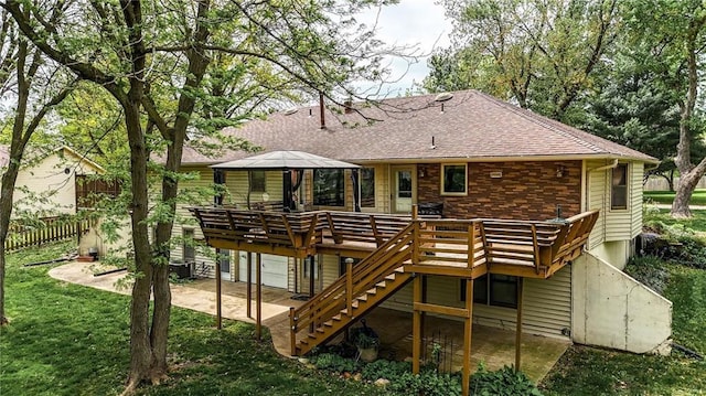 back of property featuring a wooden deck, fence, stairs, a shingled roof, and a yard