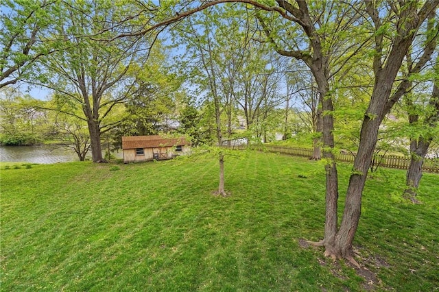 view of yard with fence, an outbuilding, and a water view