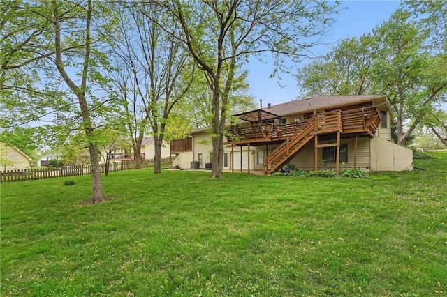 rear view of house with a yard, fence, a wooden deck, and stairs