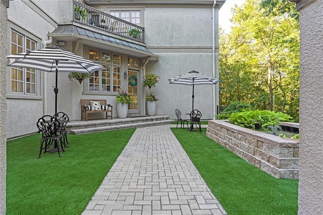 exterior space with a yard, stucco siding, and a balcony