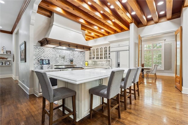 kitchen with a sink, glass insert cabinets, tasteful backsplash, and wood finished floors