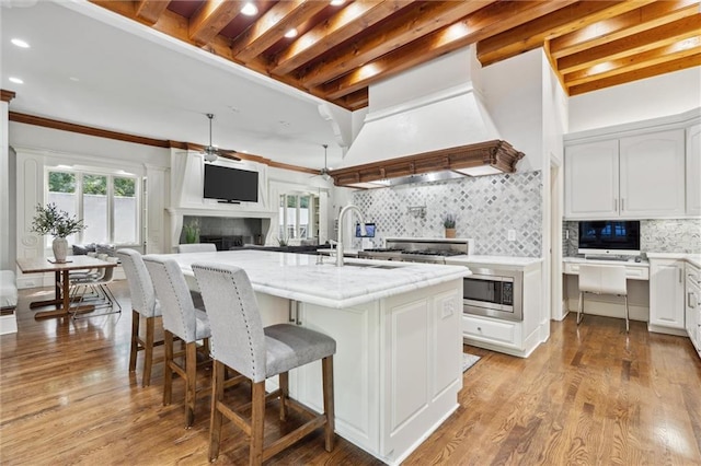 kitchen with white cabinets, tasteful backsplash, a sink, and a fireplace