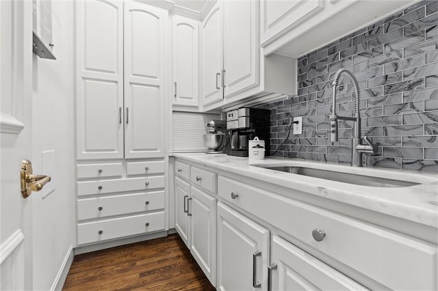 kitchen featuring a sink, white cabinets, backsplash, and dark wood-style floors