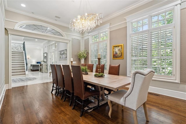 dining space featuring crown molding, wood finished floors, baseboards, stairway, and a chandelier