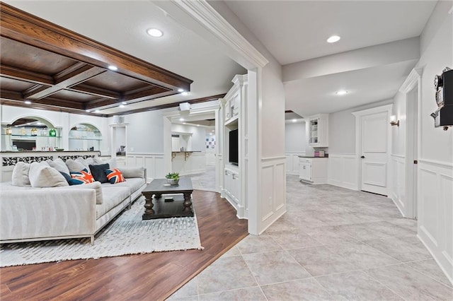living area with recessed lighting, wainscoting, a decorative wall, and beamed ceiling