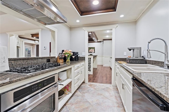 kitchen with exhaust hood, crown molding, a sink, stainless steel appliances, and white cabinetry