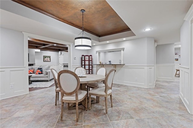 dining area with recessed lighting, a wainscoted wall, a raised ceiling, and a decorative wall