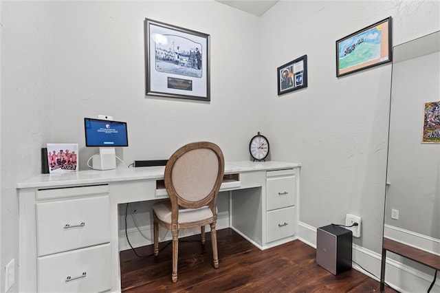 office space featuring baseboards, built in desk, and dark wood-type flooring