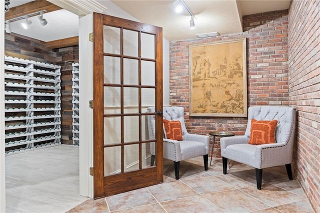 living area featuring brick wall, visible vents, track lighting, and tile patterned flooring