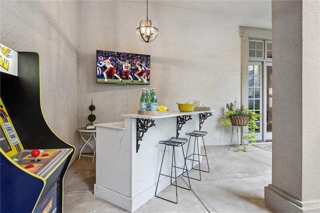 bar featuring a chandelier and unfinished concrete floors
