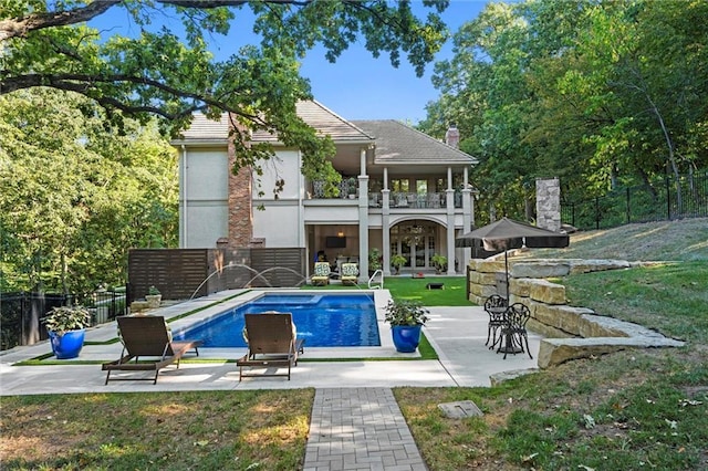 back of house with fence private yard, a patio area, stucco siding, and a balcony