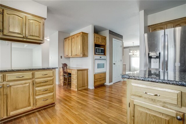 22804 E 28th Terrace Ct, Blue Springs, MO 64015 - kitchen with stainless steel appliances, light wood finished floors, dark stone countertops, a chandelier, and baseboards