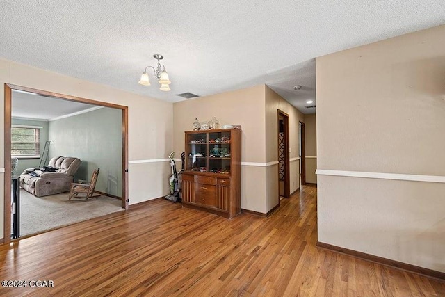 104 W Highland Ave, Nevada, MO 64772 - interior space featuring light wood-style flooring, a chandelier, baseboards, and a textured ceiling