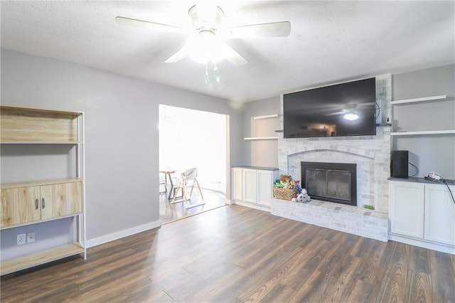 308 Acorn Pl, Warrensburg, MO 64093 - unfurnished living room with dark wood finished floors, a brick fireplace, a ceiling fan, and a textured ceiling
