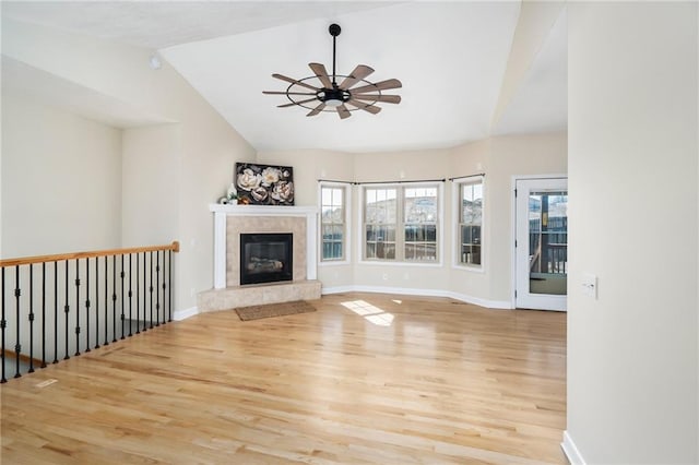 unfurnished living room featuring a ceiling fan, wood finished floors, a wealth of natural light, and a fireplace