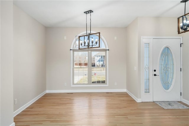 entrance foyer with light wood-style flooring, baseboards, and a chandelier