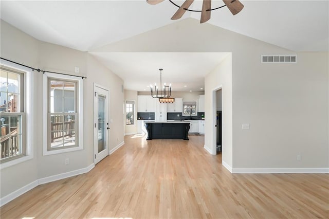 unfurnished living room featuring visible vents, ceiling fan with notable chandelier, light wood-type flooring, and baseboards