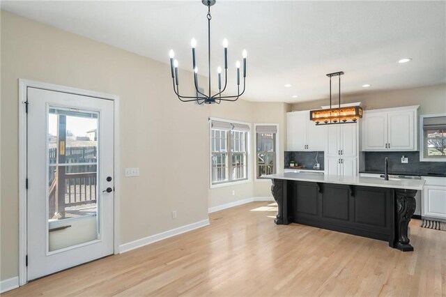 kitchen featuring baseboards, light wood-style flooring, white cabinetry, tasteful backsplash, and a chandelier