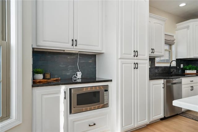 kitchen featuring recessed lighting, decorative backsplash, light wood-style floors, appliances with stainless steel finishes, and white cabinetry
