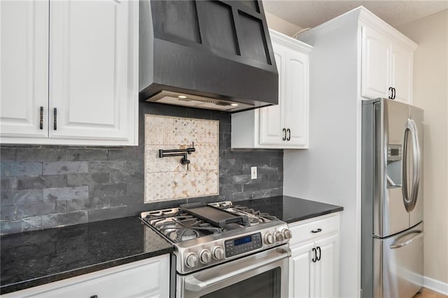 kitchen with wall chimney range hood, dark stone counters, decorative backsplash, stainless steel appliances, and white cabinetry