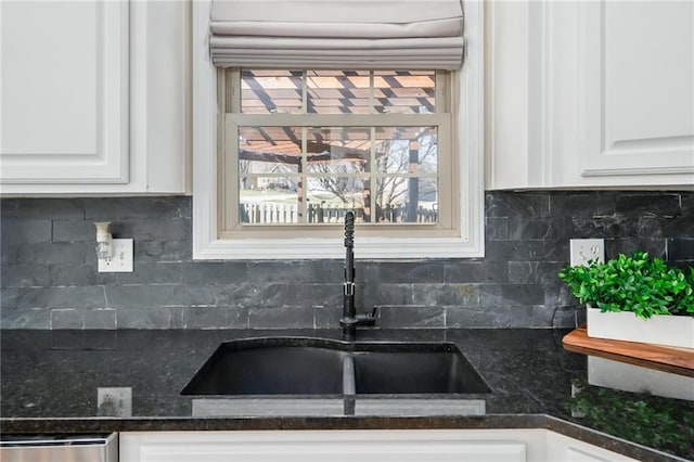 kitchen with decorative backsplash, white cabinets, stainless steel dishwasher, and a sink