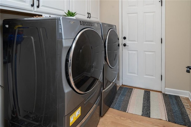laundry area with baseboards, cabinet space, and washing machine and dryer