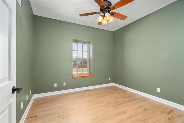 spare room featuring a ceiling fan, light wood-type flooring, and baseboards