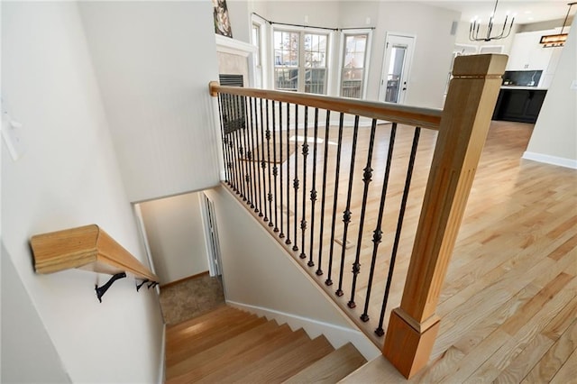 stairs with a chandelier, baseboards, and wood finished floors