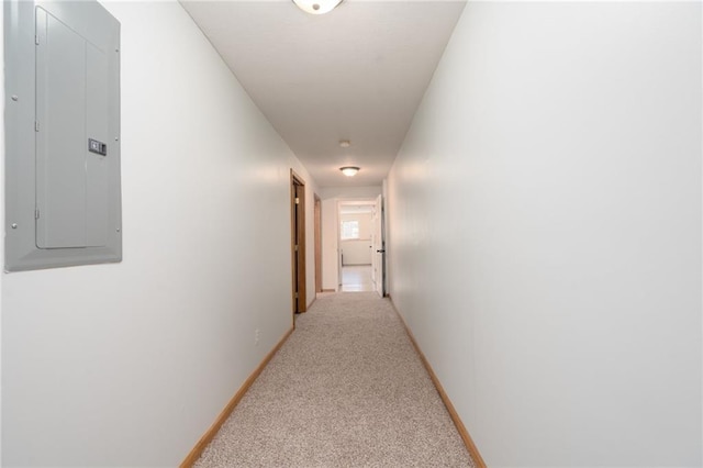 hallway with electric panel, light colored carpet, and baseboards