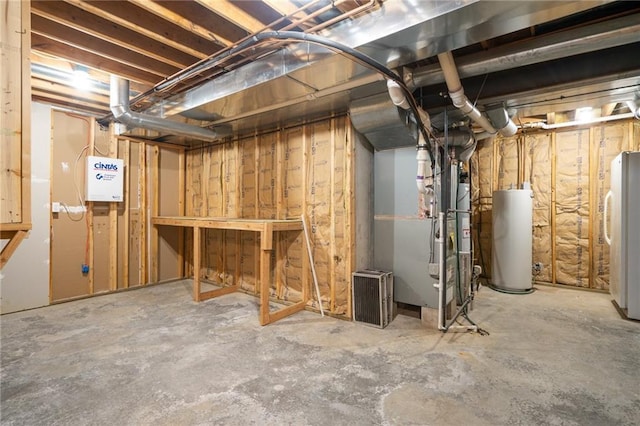 unfinished below grade area with water heater, heating unit, and freestanding refrigerator