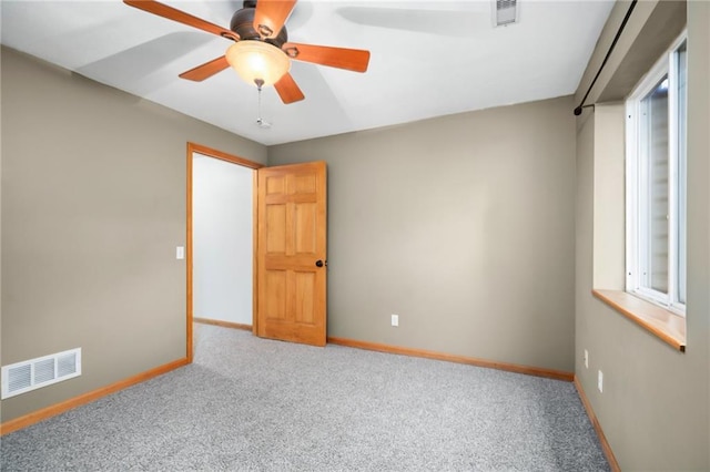 carpeted spare room with visible vents, ceiling fan, and baseboards