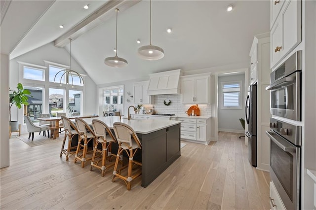 12313 W 169th St, Overland Park, KS 66221 - kitchen featuring stainless steel appliances, custom range hood, beamed ceiling, light countertops, and a center island with sink