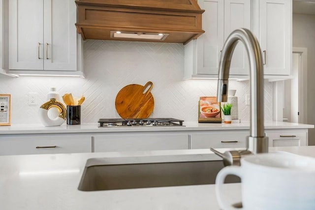 13021 W 174th Pl, Overland Park, KS 66221 - kitchen view of light countertops, premium range hood, tasteful backsplash, white cabinets, and stainless steel gas cooktop
