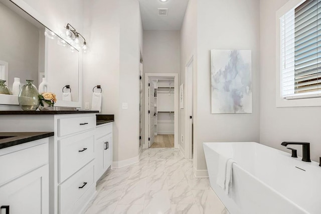 13021 W 174th Pl, Overland Park, KS 66221 - full bathroom with marble look tiles, a freestanding tub, a walk in closet, vanity, and baseboards