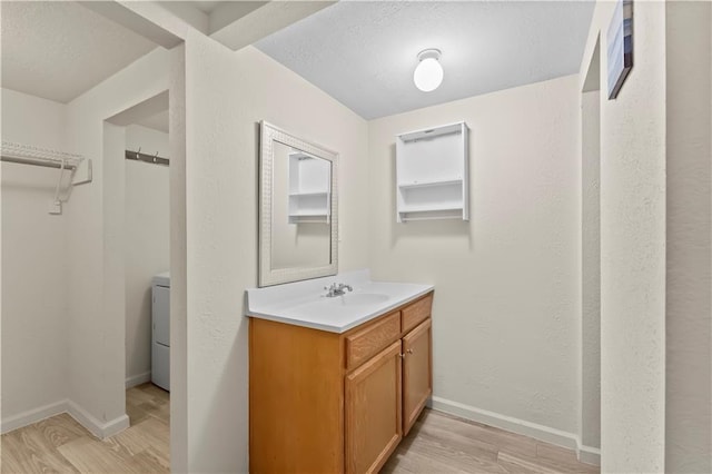 607 SW 8th St, Blue Springs, MO 64015 - bathroom with vanity, wood finished floors, baseboards, washer / clothes dryer, and a textured ceiling