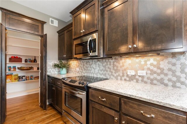 16487 W 166th Pl, Olathe, KS 66062 - kitchen with stainless steel appliances, dark brown cabinetry, light wood-style flooring, light stone counters, and tasteful backsplash