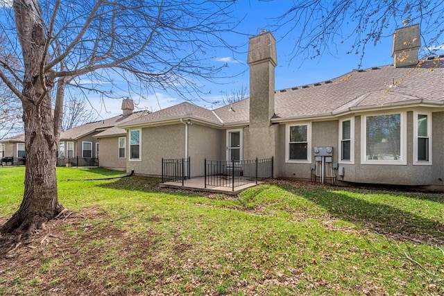 rear view of property with a lawn, a chimney, and stucco siding