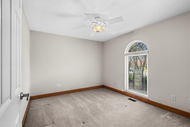 carpeted empty room with baseboards, ceiling fan, and visible vents