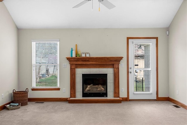 unfurnished living room featuring carpet flooring, visible vents, a tiled fireplace, and a ceiling fan