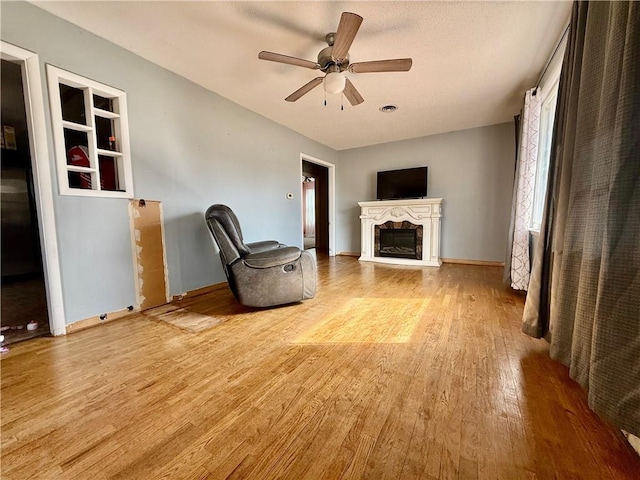 611 E Elm St, Hardin, MO 64035 - unfurnished living room with light wood-type flooring, ceiling fan, and a fireplace with raised hearth