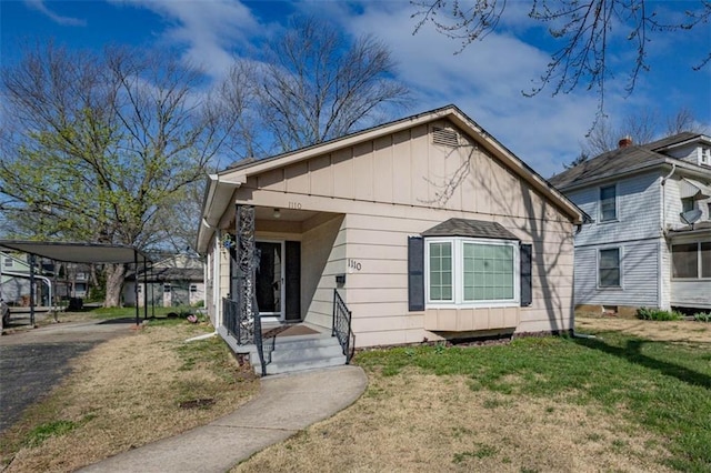 bungalow-style home featuring a detached carport and a front yard