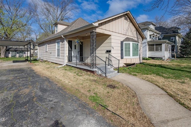 bungalow-style house featuring a front yard, board and batten siding, and aphalt driveway