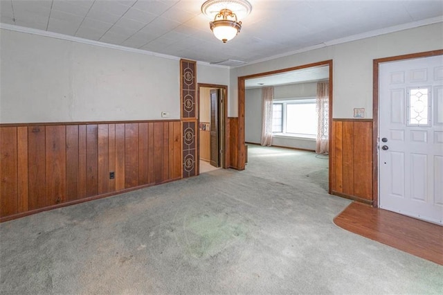 carpeted foyer entrance featuring crown molding, wood walls, and wainscoting