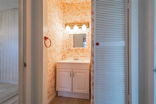 bathroom featuring wallpapered walls, vanity, and baseboards