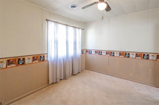 carpeted empty room with visible vents and a ceiling fan