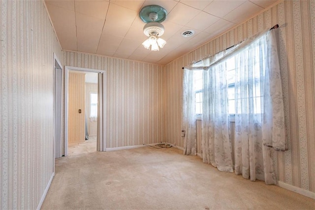 empty room with wallpapered walls, carpet floors, baseboards, and visible vents