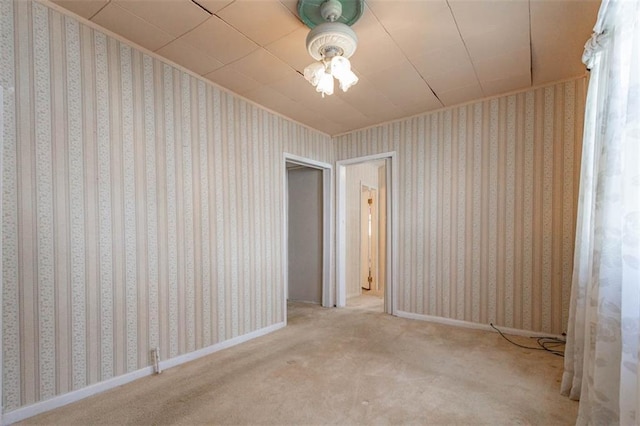 spare room featuring baseboards, wallpapered walls, and carpet flooring