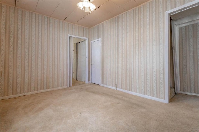 empty room with carpet flooring, wallpapered walls, and baseboards